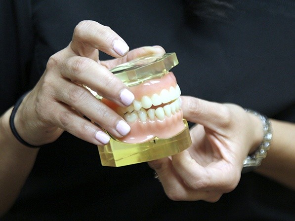 Person holding model of implant denture