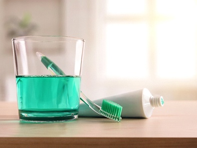 Green mouthwash toothbrush and toothpaste resting on countertop