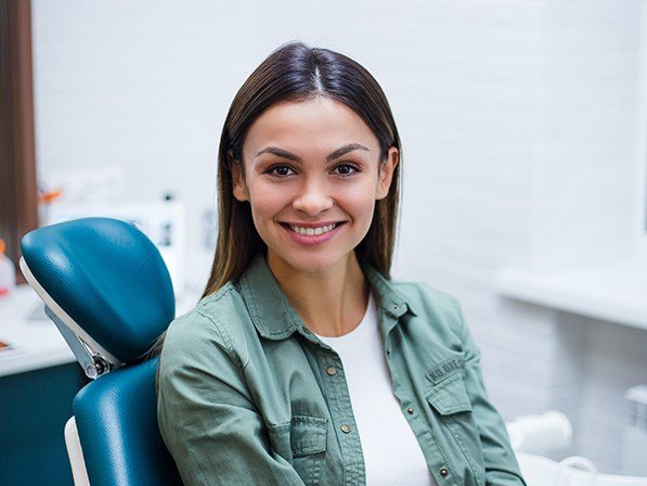 Woman in dental chair smiling after impacted tooth treatment