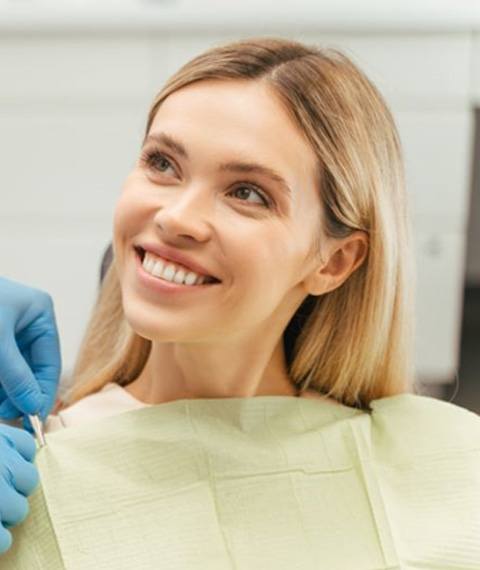 Dental patient smiling while team member secures her dental bib