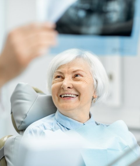 Senior woman smiling at oral surgeon after getting Teeth in a Day in Dallas