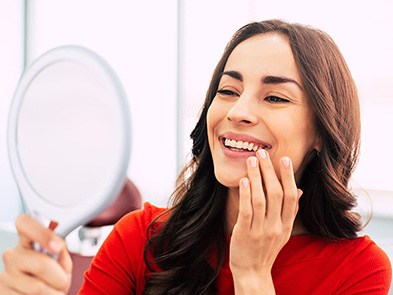 Woman in dental chair admiring her smile in mirror