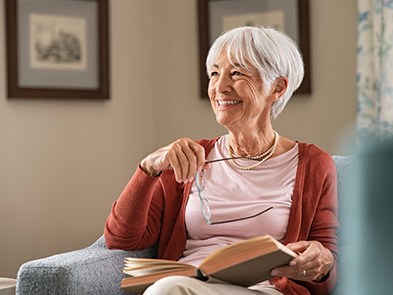 Senior woman sitting in couch with book in lap