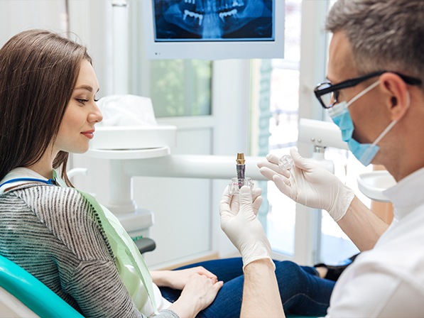 Dentist showing patient a dental implant model