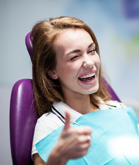 Woman giving thumbs up after wisdom tooth removals