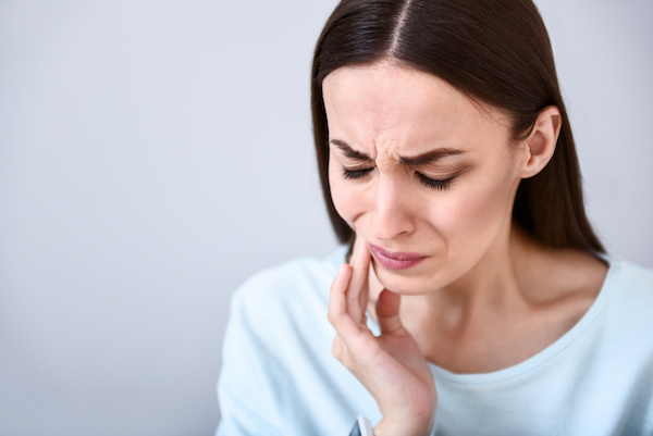 woman wincing with toothache touching jaw 